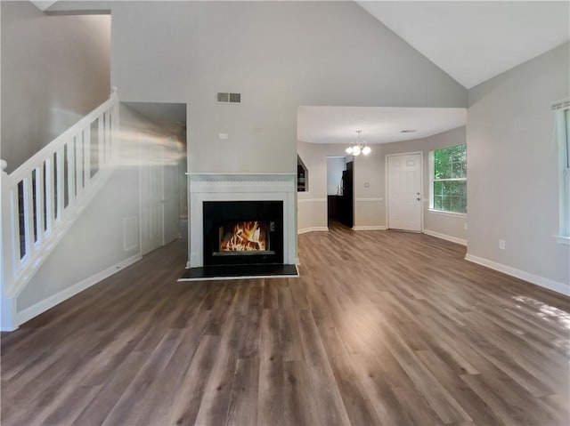 unfurnished living room featuring high vaulted ceiling, an inviting chandelier, and dark hardwood / wood-style floors