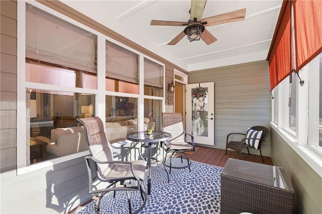 sunroom featuring wood walls, a ceiling fan, and wood finished floors