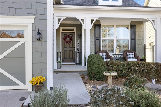 property entrance featuring covered porch, roof with shingles, and a garage