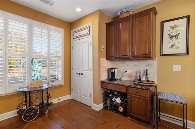 entrance foyer with a dry bar, recessed lighting, baseboards, visible vents, and dark wood-type flooring
