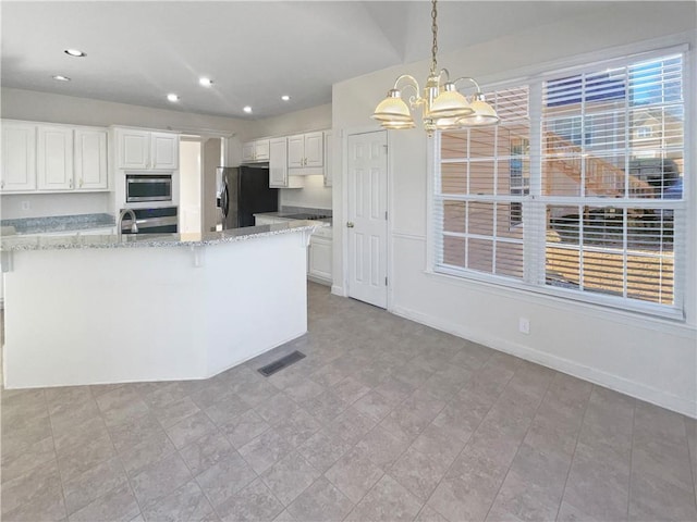 kitchen featuring appliances with stainless steel finishes, light stone counters, a notable chandelier, white cabinets, and decorative light fixtures