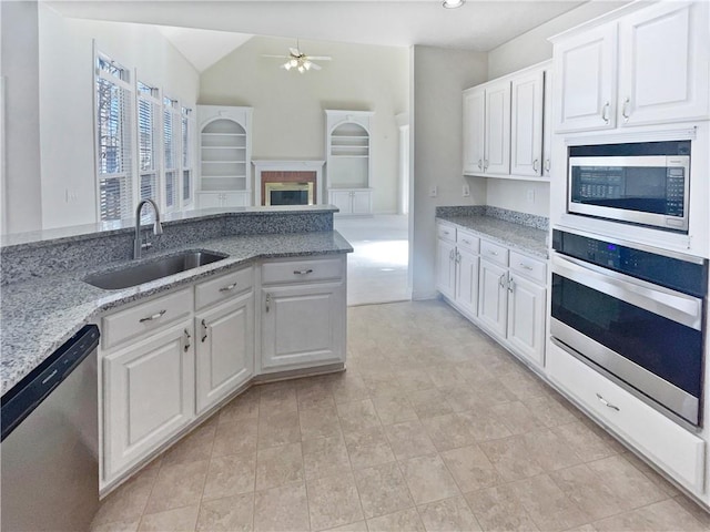 kitchen featuring vaulted ceiling, appliances with stainless steel finishes, sink, white cabinets, and ceiling fan