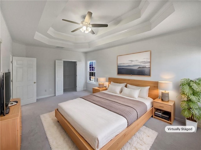 carpeted bedroom featuring ceiling fan, ornamental molding, and a tray ceiling