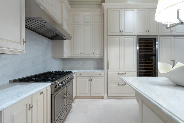 kitchen featuring wall chimney exhaust hood, high end stainless steel range oven, wine cooler, and white cabinetry