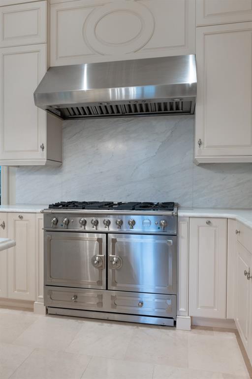 kitchen featuring white cabinets, light countertops, tasteful backsplash, exhaust hood, and range with two ovens