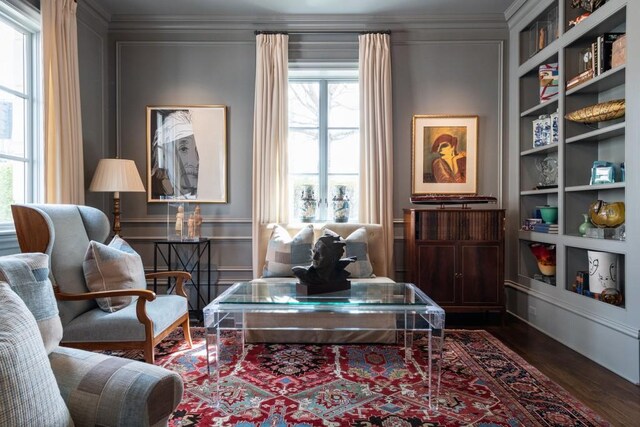 living area with dark wood-style floors, built in features, and ornamental molding