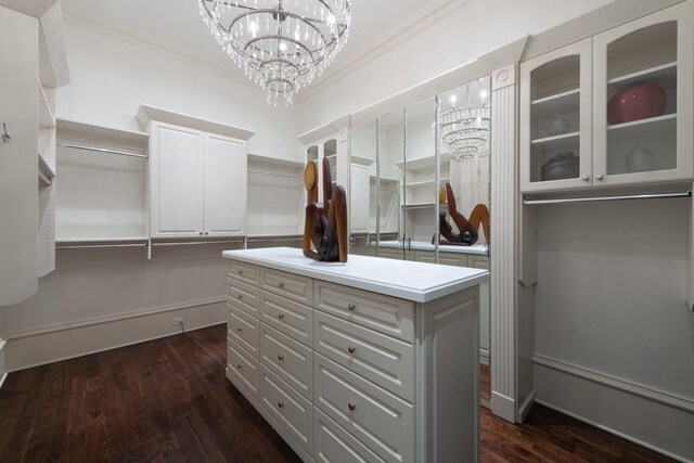 walk in closet with dark wood-style flooring and an inviting chandelier