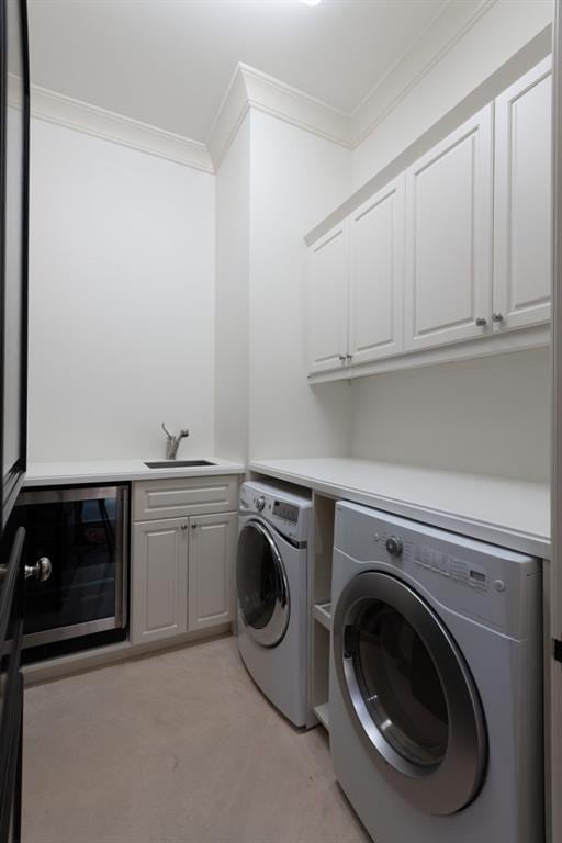 washroom with beverage cooler, cabinet space, washer and clothes dryer, crown molding, and a sink