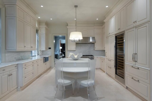 kitchen featuring decorative light fixtures, under cabinet range hood, stove, a sink, and light countertops