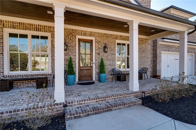 doorway to property featuring covered porch and brick siding