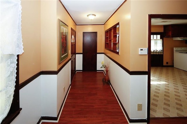 hallway with washer / dryer, dark hardwood / wood-style floors, and ornamental molding