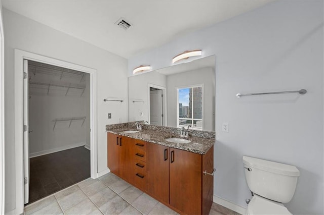 943 Peachtree St NE Unit 1518, Atlanta, GA 30309 - full bath featuring double vanity, toilet, baseboards, a walk in closet, and tile patterned floors