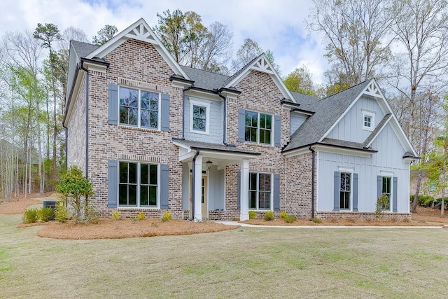 craftsman house with board and batten siding, a front yard, and brick siding