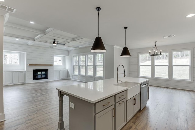 kitchen with ceiling fan, a sink, light wood-style floors, a glass covered fireplace, and recessed lighting