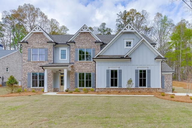 craftsman-style house with board and batten siding, a front yard, and brick siding