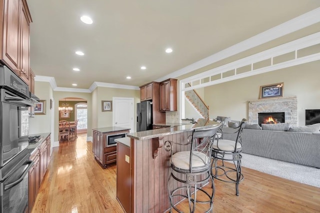 2740 Heritage Bend Ct SW, Grayson, GA 30017 - kitchen with arched walkways, stainless steel appliances, crown molding, a kitchen bar, and light wood-style floors
