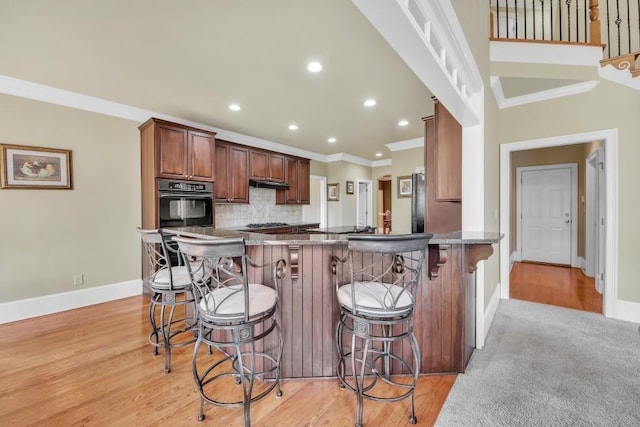 2740 Heritage Bend Ct SW, Grayson, GA 30017 - kitchen featuring black oven, ornamental molding, baseboards, decorative backsplash, and a breakfast bar area