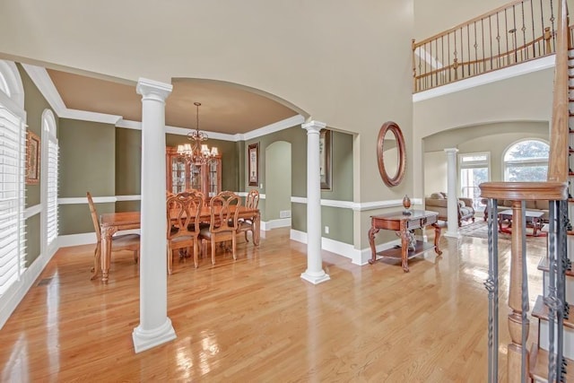 2740 Heritage Bend Ct SW, Grayson, GA 30017 - dining area with arched walkways, light wood-style floors, ornate columns, ornamental molding, and a towering ceiling