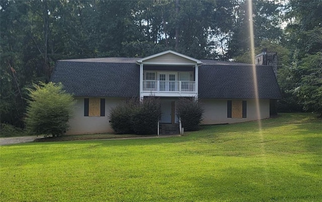 view of property featuring a balcony and a front yard