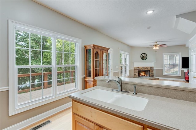 4039 Sargent Cir, Gainesville, GA 30506 - kitchen with a sink, a fireplace, a ceiling fan, light countertops, and a textured ceiling