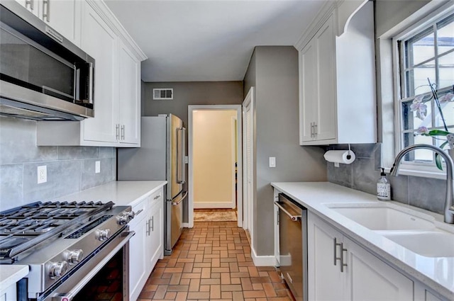 kitchen featuring a sink, stainless steel appliances, visible vents, and white cabinets