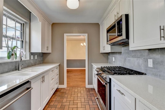 kitchen with light countertops, baseboards, appliances with stainless steel finishes, and a sink