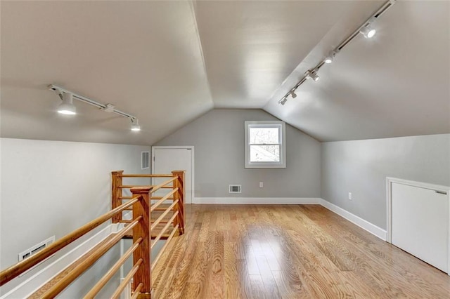 additional living space featuring lofted ceiling, wood finished floors, visible vents, and baseboards