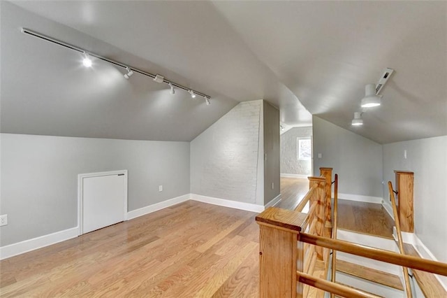 bonus room with baseboards, light wood-style floors, and vaulted ceiling