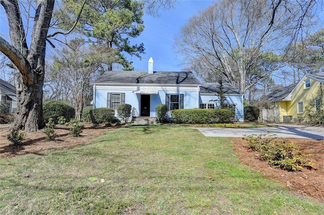 view of front of property with stucco siding, driveway, a chimney, and a front yard