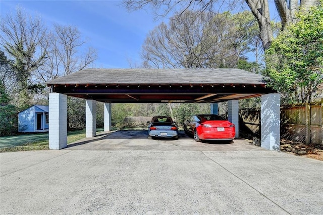 view of parking / parking lot featuring aphalt driveway, fence, and a carport