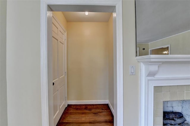 interior details featuring baseboards, wood finished floors, and a tiled fireplace