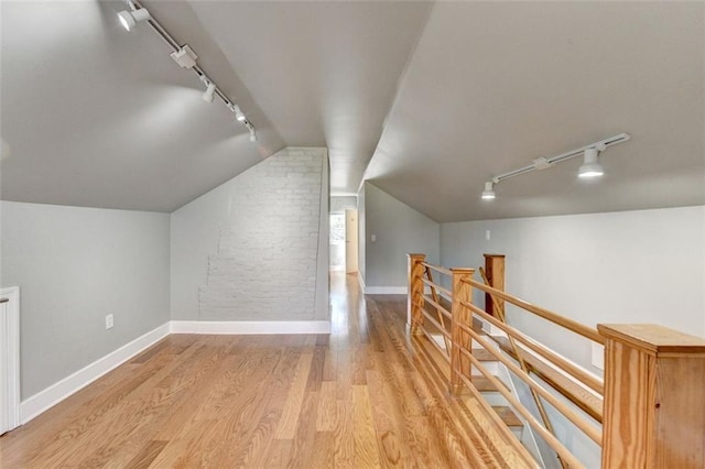 additional living space with vaulted ceiling, wood finished floors, and baseboards