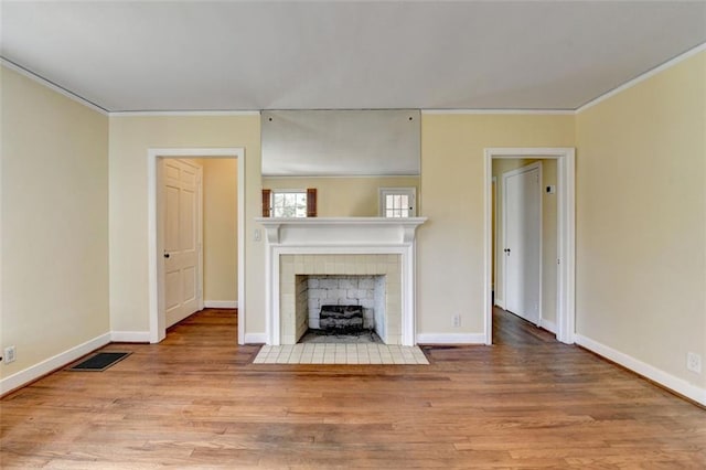 unfurnished living room featuring visible vents, ornamental molding, a fireplace, and wood finished floors