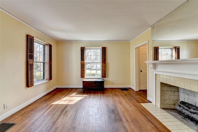 unfurnished living room with ornamental molding, wood finished floors, visible vents, and baseboards