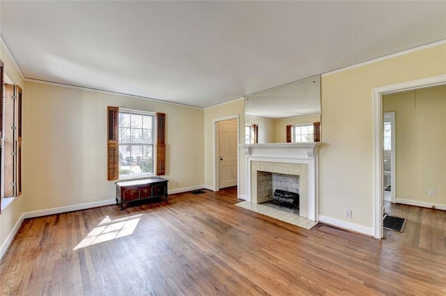 unfurnished living room featuring baseboards, wood finished floors, a fireplace, and ornamental molding