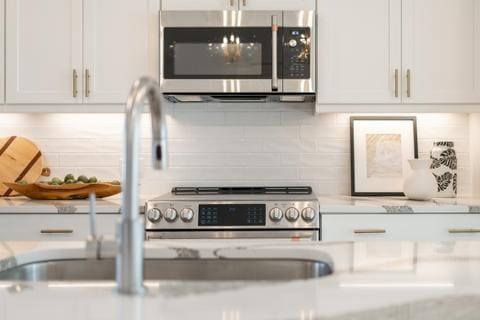 388 Pratt Dr Unit 2113, Atlanta, GA 30315 - kitchen featuring stainless steel microwave, light countertops, white cabinetry, and decorative backsplash