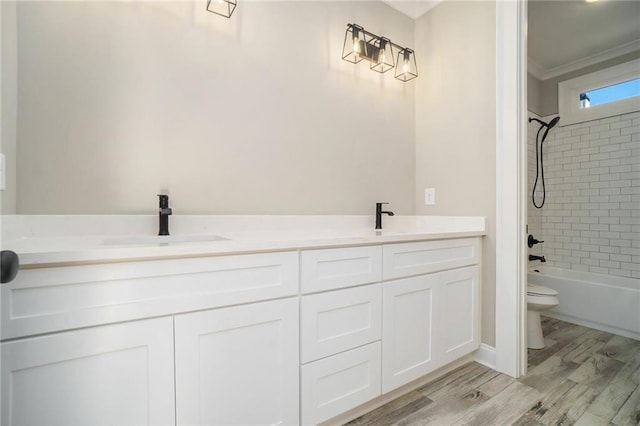 bathroom with toilet, double vanity, wood finished floors, washtub / shower combination, and crown molding