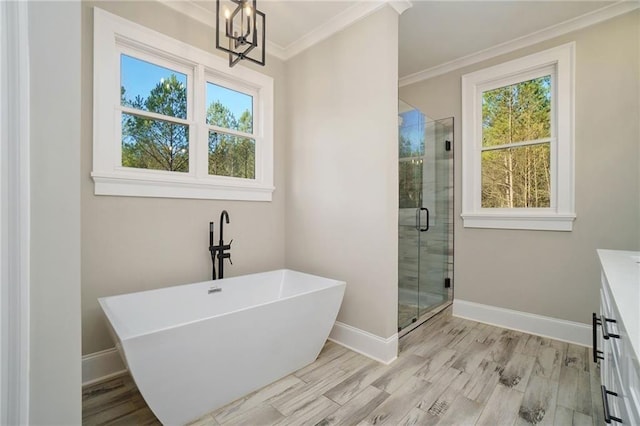 full bathroom with crown molding, a shower stall, a chandelier, baseboards, and a freestanding bath