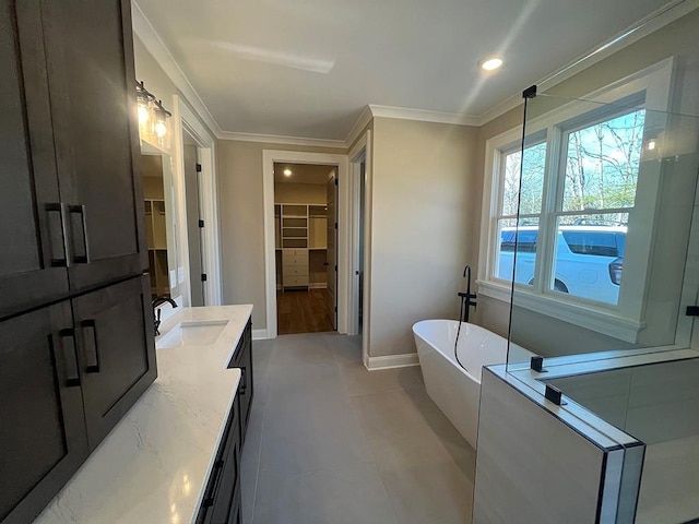 full bath featuring a freestanding tub, crown molding, a spacious closet, vanity, and baseboards