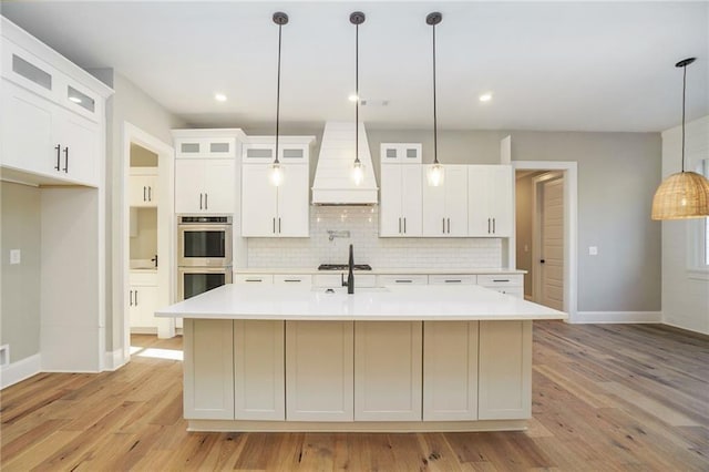 kitchen with appliances with stainless steel finishes, custom range hood, baseboards, light countertops, and decorative backsplash