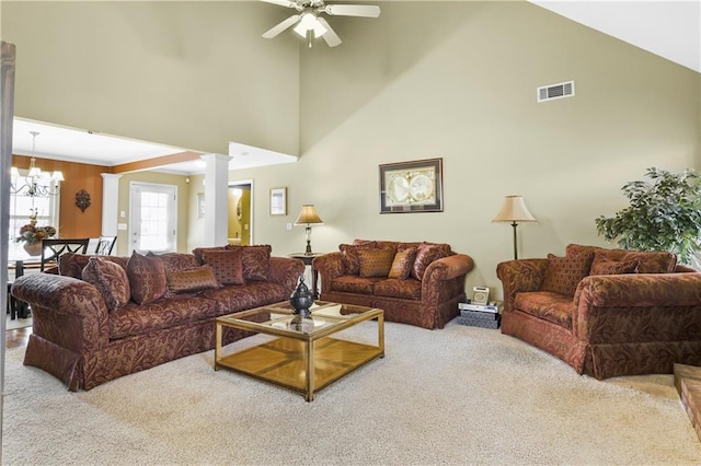 living room with ornate columns, a towering ceiling, carpet floors, and ceiling fan with notable chandelier