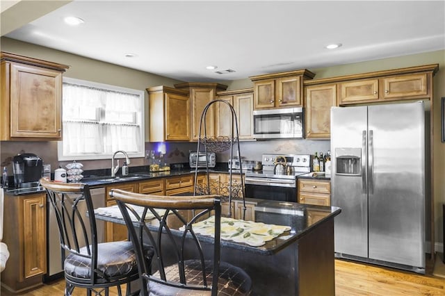 kitchen with stainless steel appliances, a kitchen island, dark stone countertops, and sink