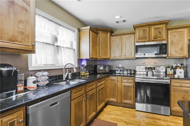 kitchen with dark stone countertops, light hardwood / wood-style floors, sink, and stainless steel appliances