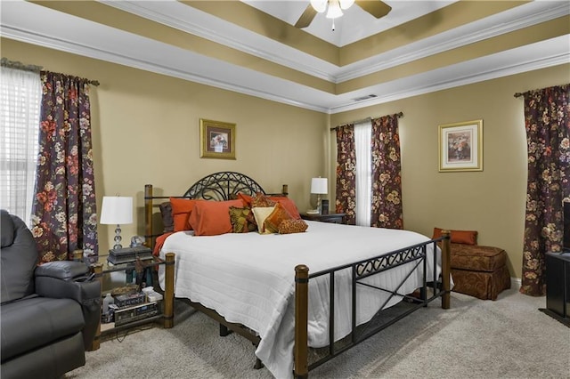 bedroom with ceiling fan, a raised ceiling, light carpet, and multiple windows