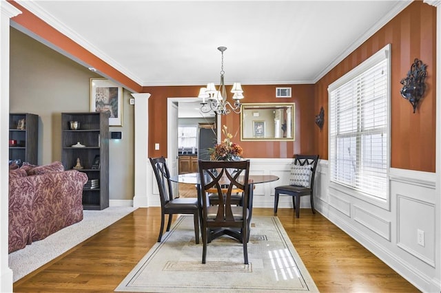 dining room featuring crown molding, hardwood / wood-style flooring, and an inviting chandelier