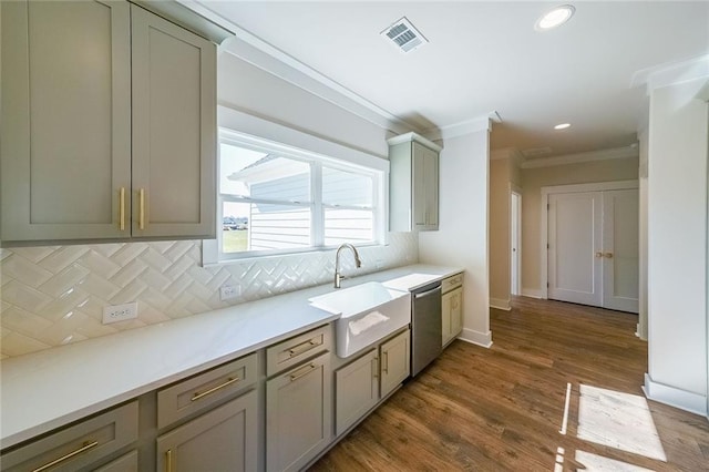 kitchen featuring tasteful backsplash, dishwasher, ornamental molding, light countertops, and a sink