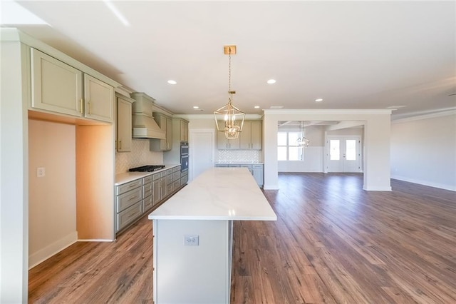 kitchen with tasteful backsplash, a kitchen island, custom exhaust hood, pendant lighting, and black gas stovetop