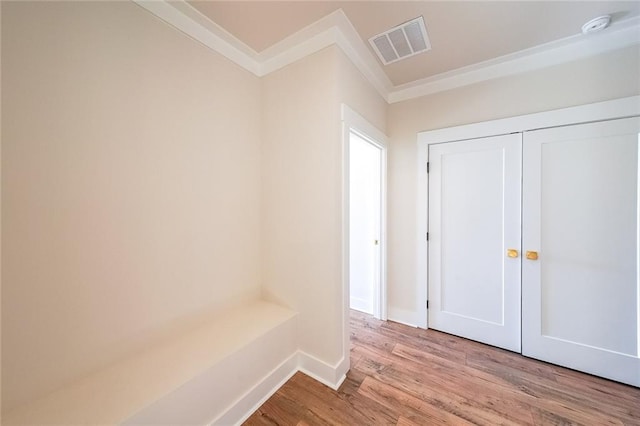 interior space featuring light wood-type flooring, baseboards, visible vents, and ornamental molding