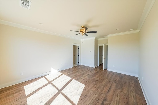 spare room with wood finished floors, visible vents, and baseboards