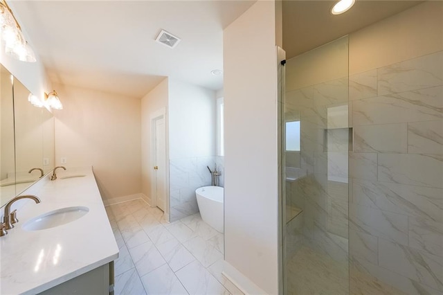 full bathroom with double vanity, marble finish floor, a sink, and a soaking tub